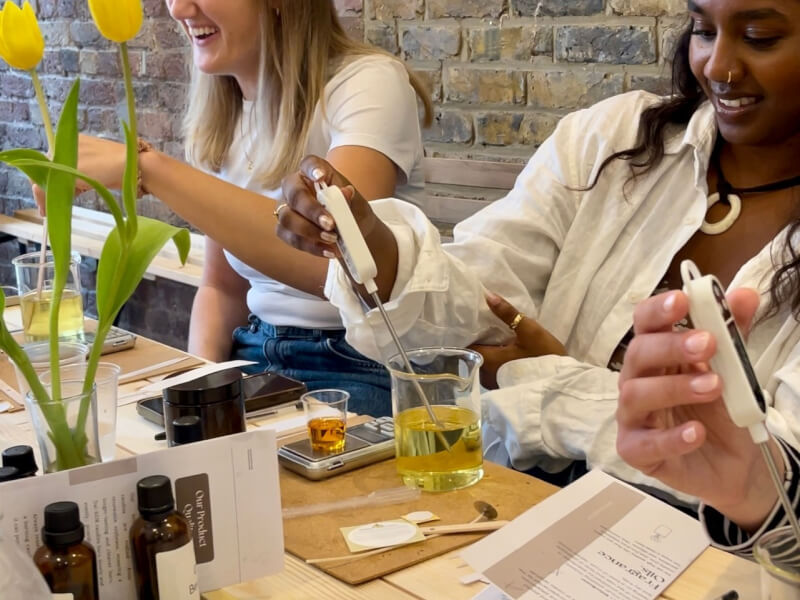 Two women are laughing and making candles at a candle making class